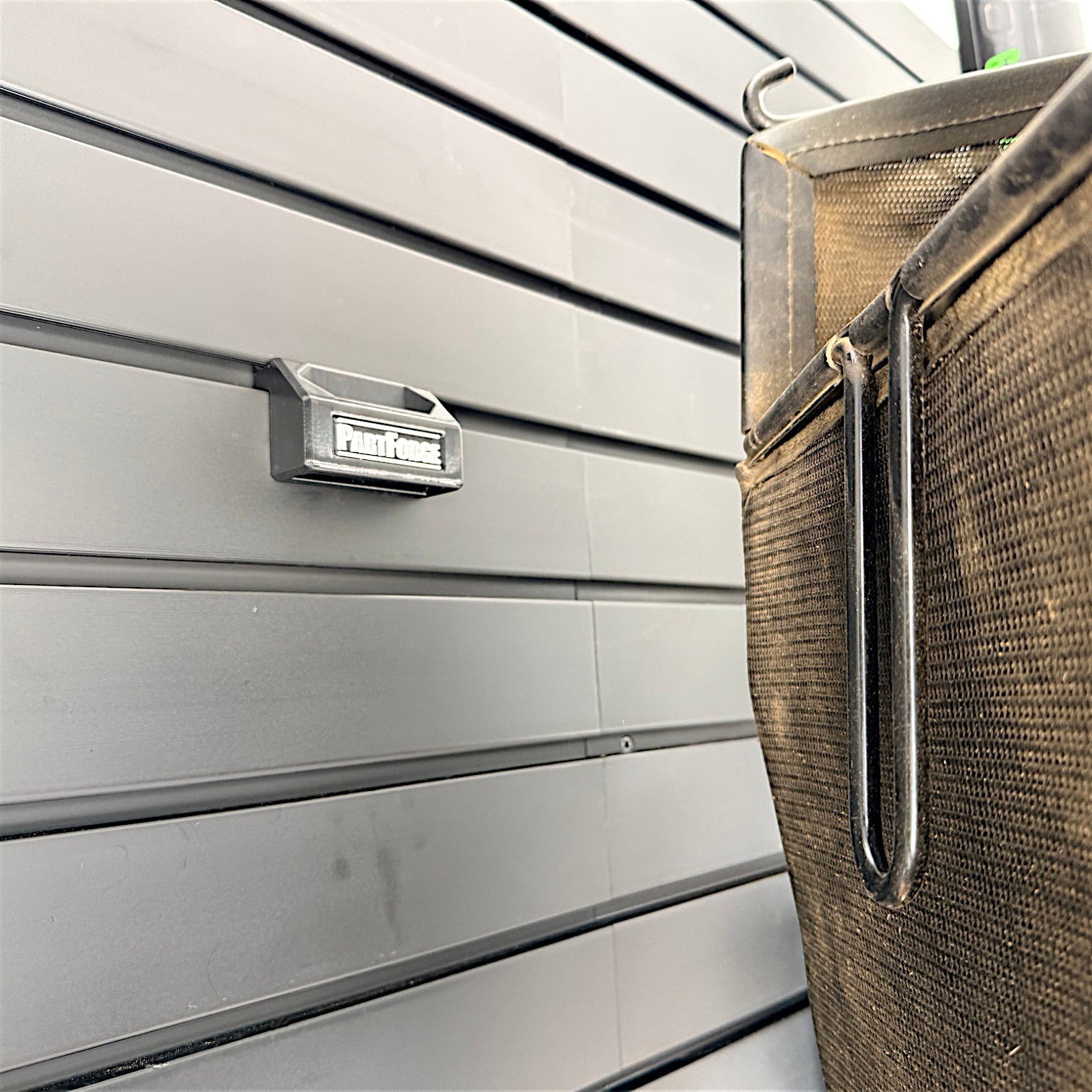 PartForge mounting bracket for EGO mower bags installed on a Gladiator GearWall panel with mower bag handle shown